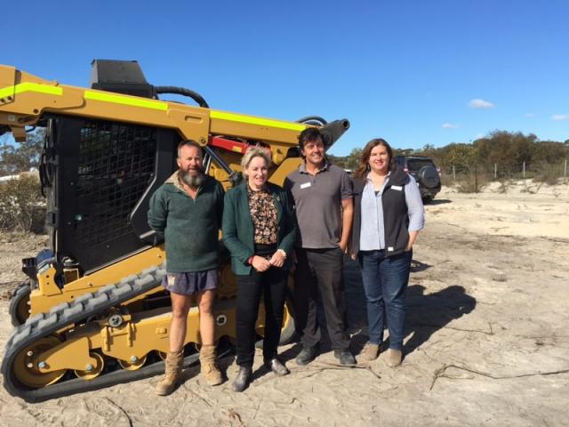 A team of DPIRD staff responsible for managing construction of the State Barrier Fence Esperance extension, with the Minister for Agriculture and Food, in front of a bobcat.