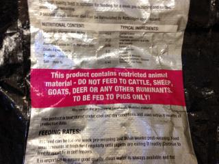 Bag of pig feed labelled with a statement indicating the feed contains restricted animal material.