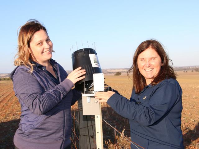 Two female DPIRD staff with a electronic rain gauge