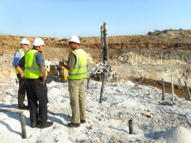 three men standing in an open mining pit for agricultural lime
