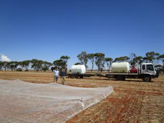 Two men in a trial paddock with a mobile irrigation unit behind.